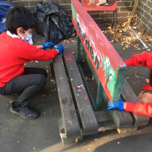 Children from Walker Children's Club help paint a bench in the garden