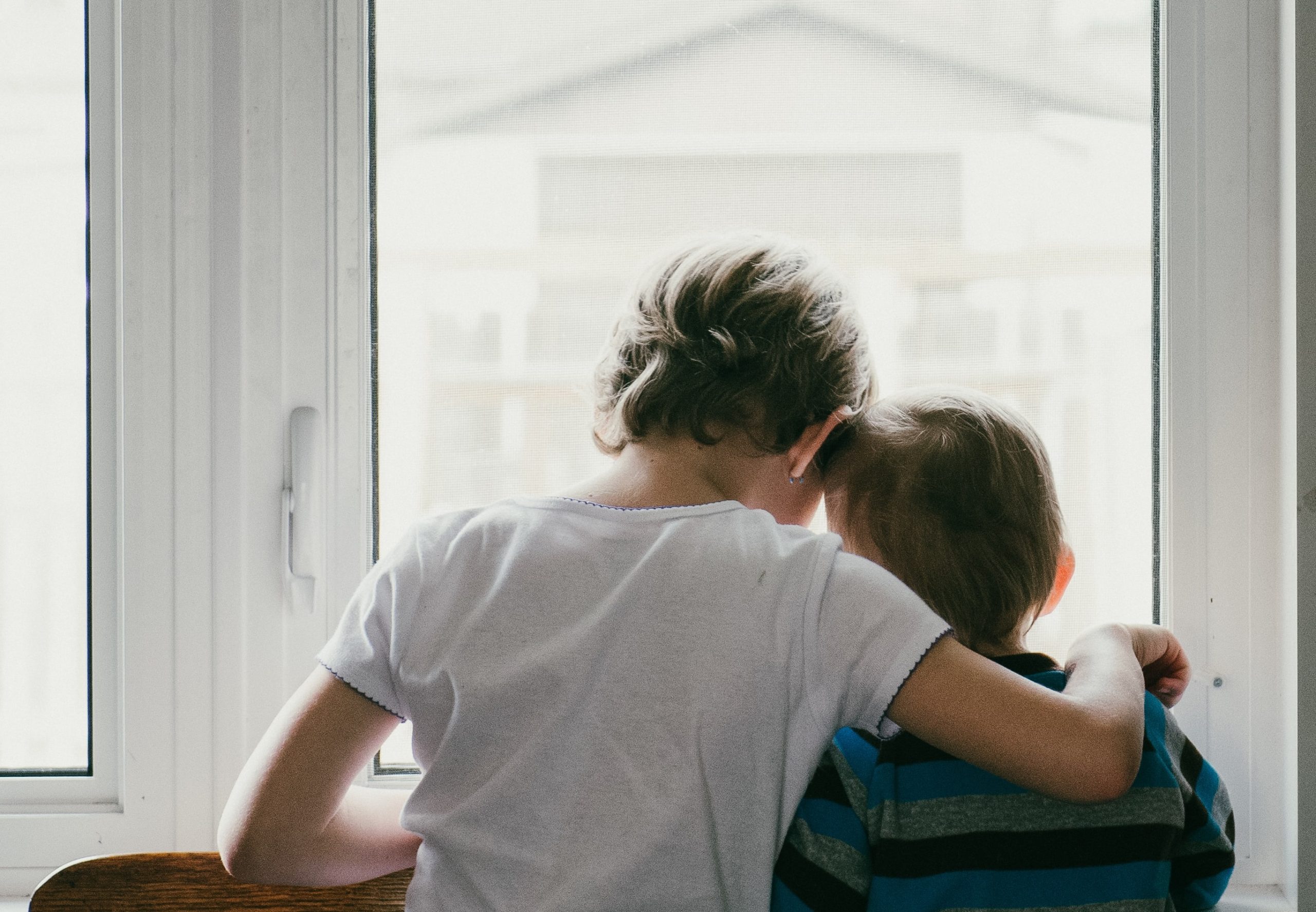 Two children looking out a window (credit Jess Zoerb via Unsplash)