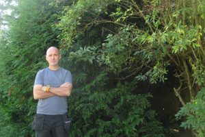 Jon Woods beside the trees that are blocking light to his property