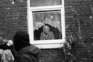 An elderly woman looks out of a window