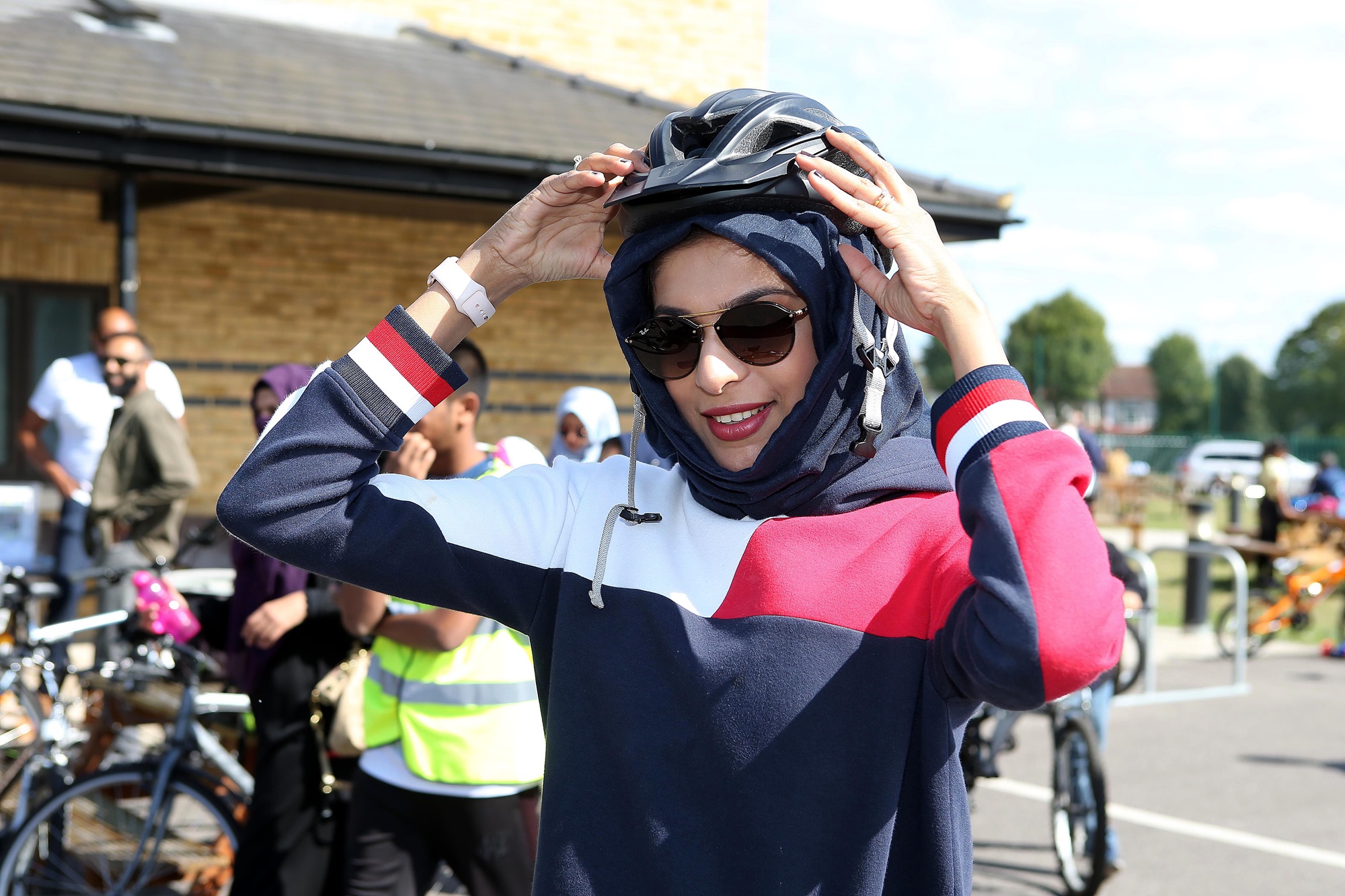 A cyclist puts on her helmet