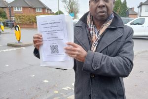 Stephen Wilson at the junction, holding his petition to the council
