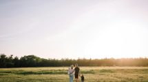 Two people and a child stand admiring a sunset