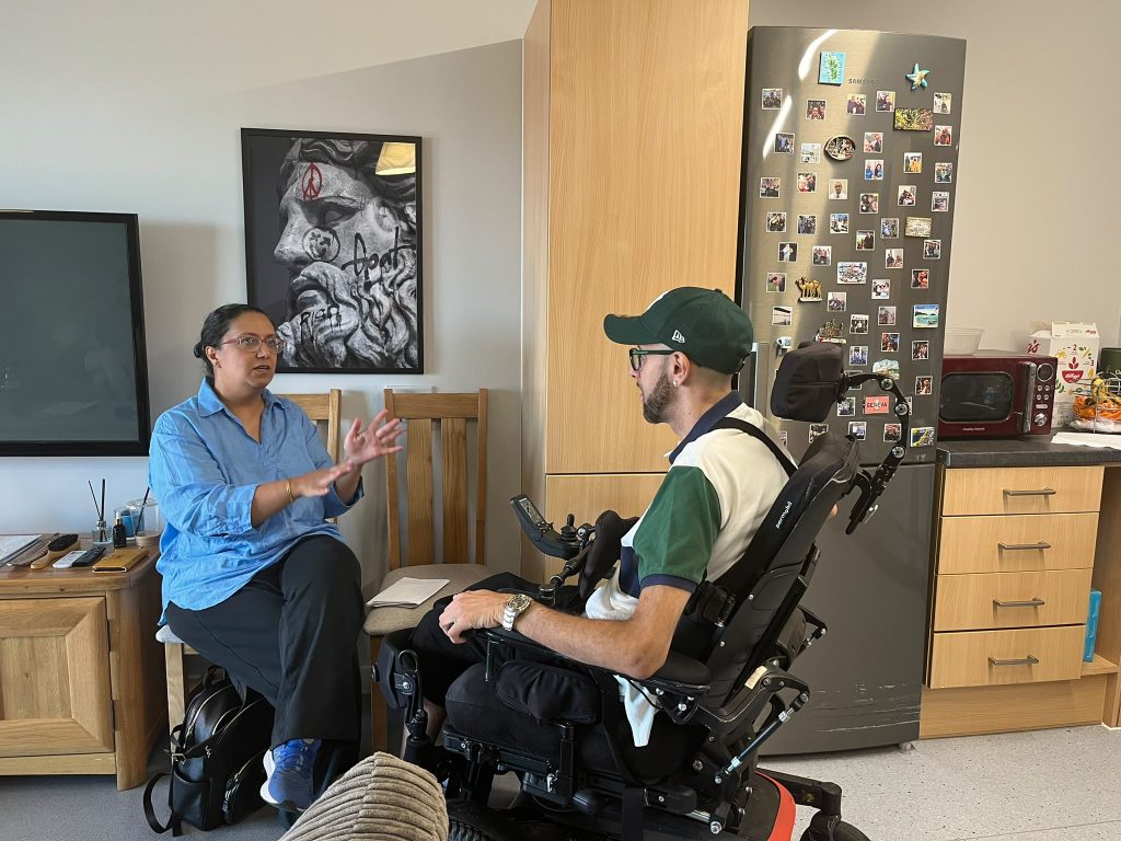 A woman sitting on a chair talking to a man in a wheelchair