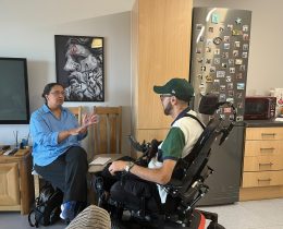 A woman sitting on a chair talking to a man in a wheelchair