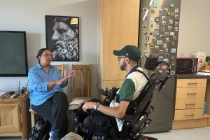 A woman sitting on a chair talking to a man in a wheelchair