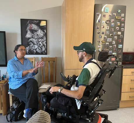 A woman sitting on a chair talking to a man in a wheelchair