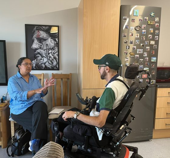 A woman sitting on a chair talking to a man in a wheelchair