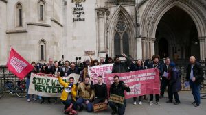 A group of people standing outside a courthouse holding placards