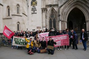A group of people standing outside a courthouse holding placards
