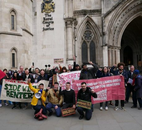 A group of people standing outside a courthouse holding placards